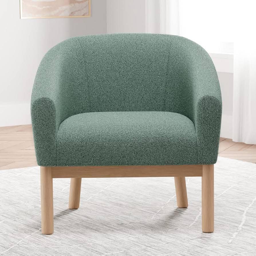 Sillón individual curvo tapizado en tela tipo bouclé con patas de madera
